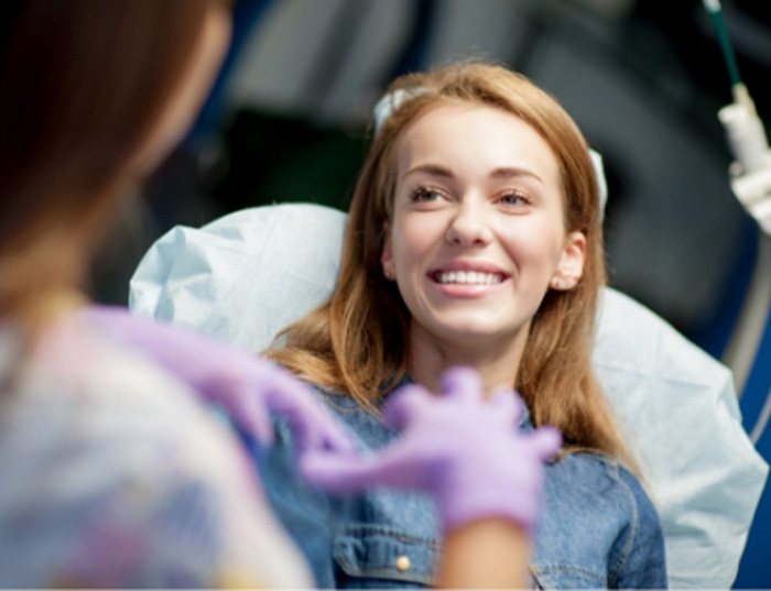 woman smiling in mirror after getting dental implants